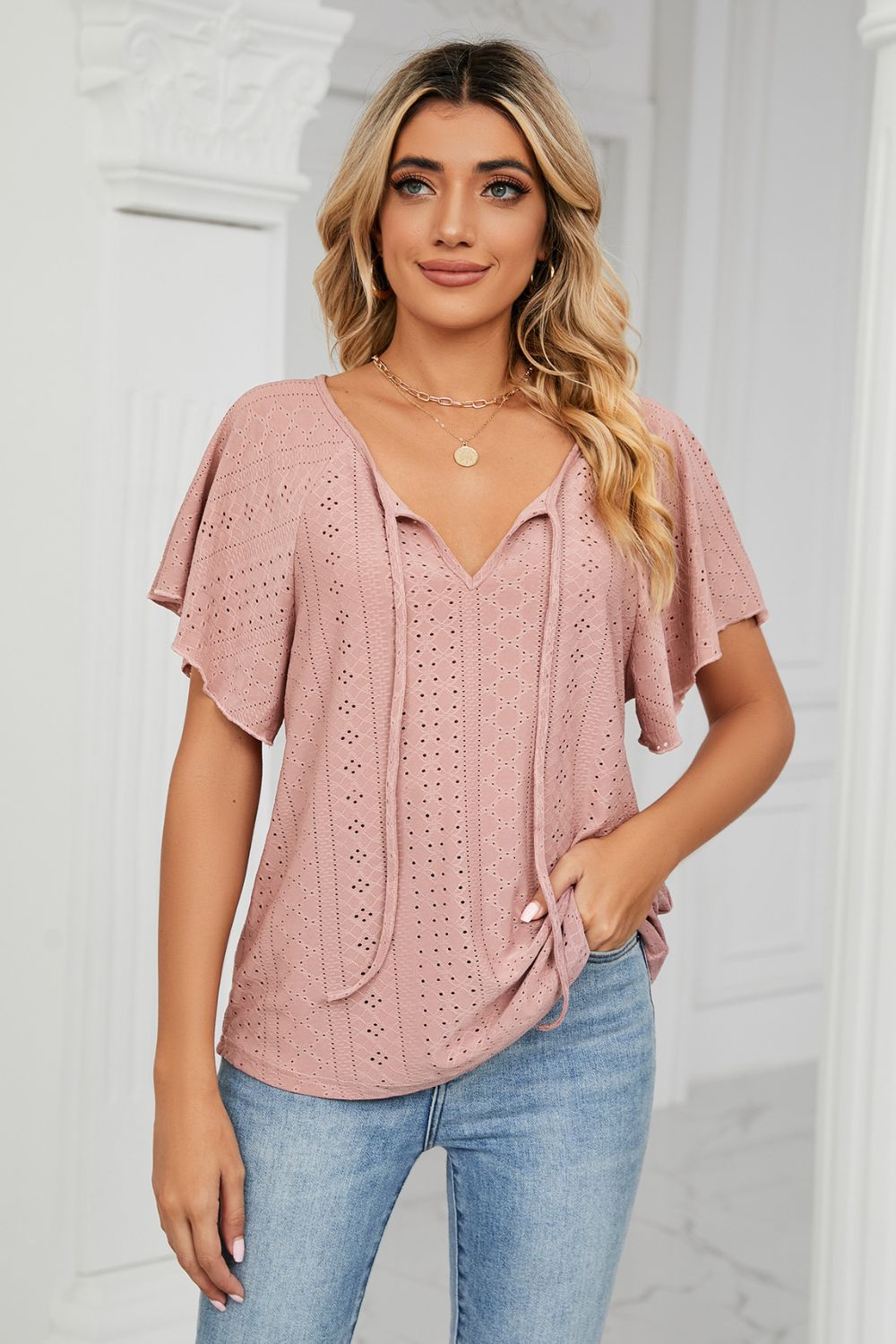 Pink eyelet tie-neck flutter sleeve blouse front view on model