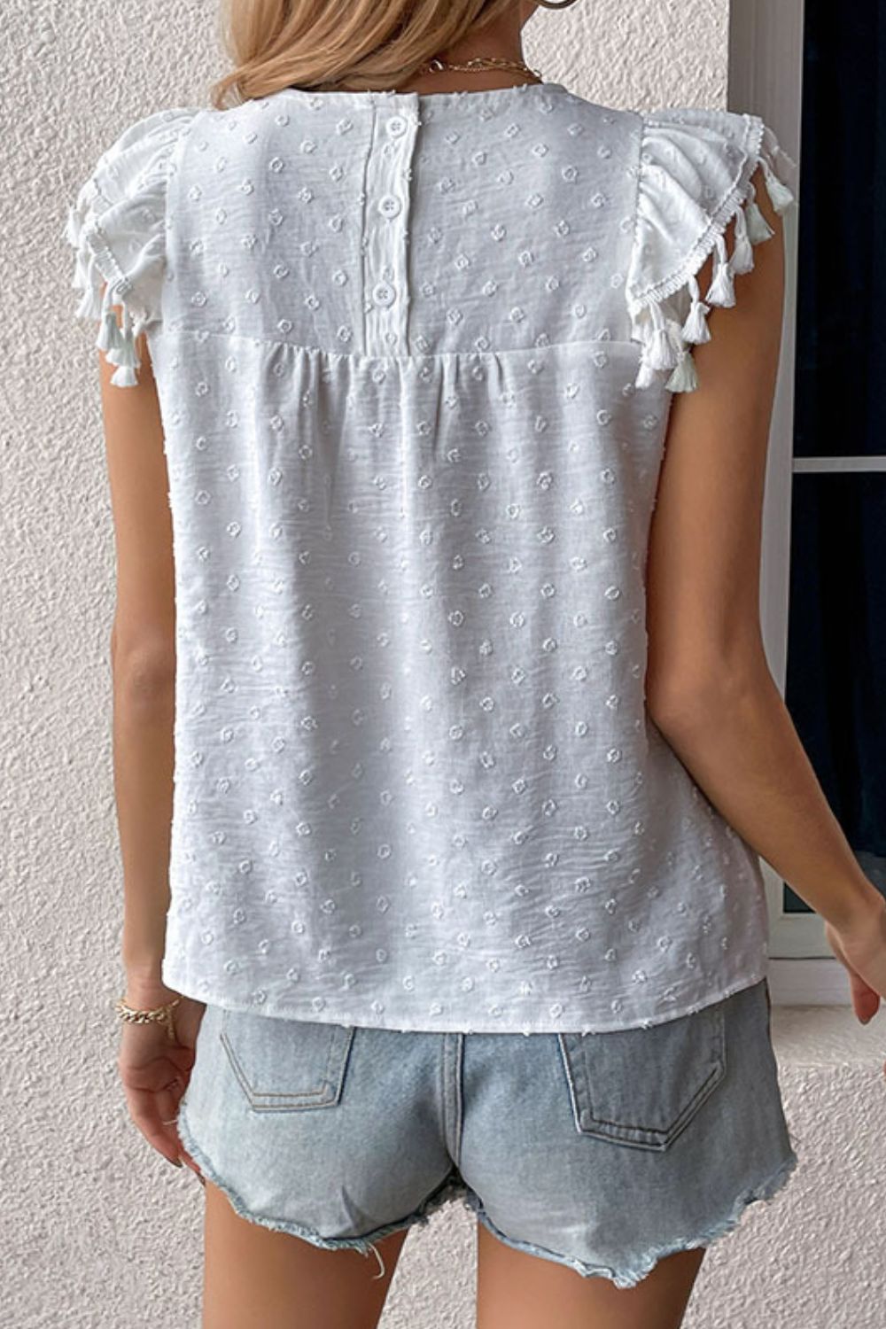 Back view of white Swiss dot tassel sleeve blouse on model